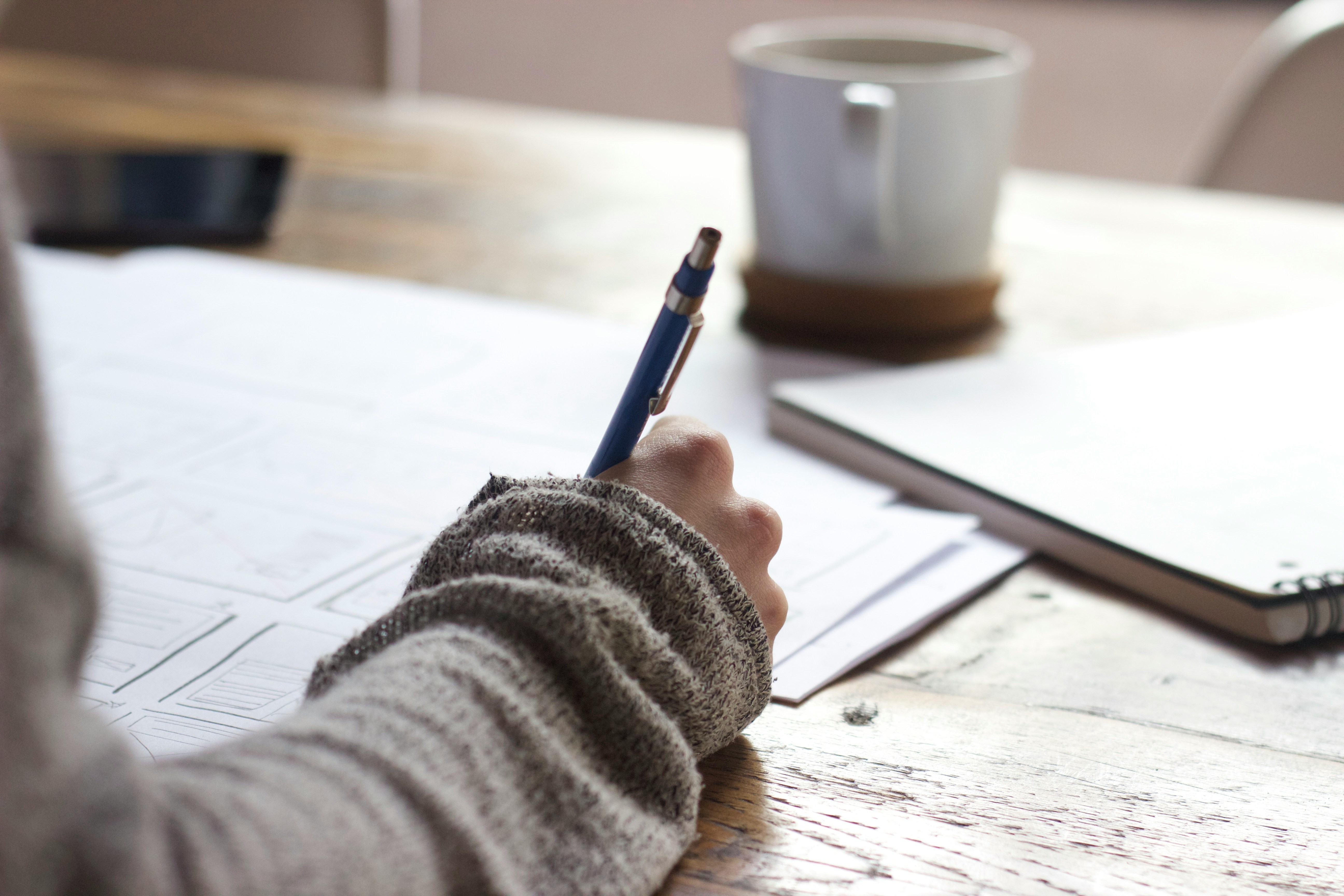 A woman's hand writing on a notebook.