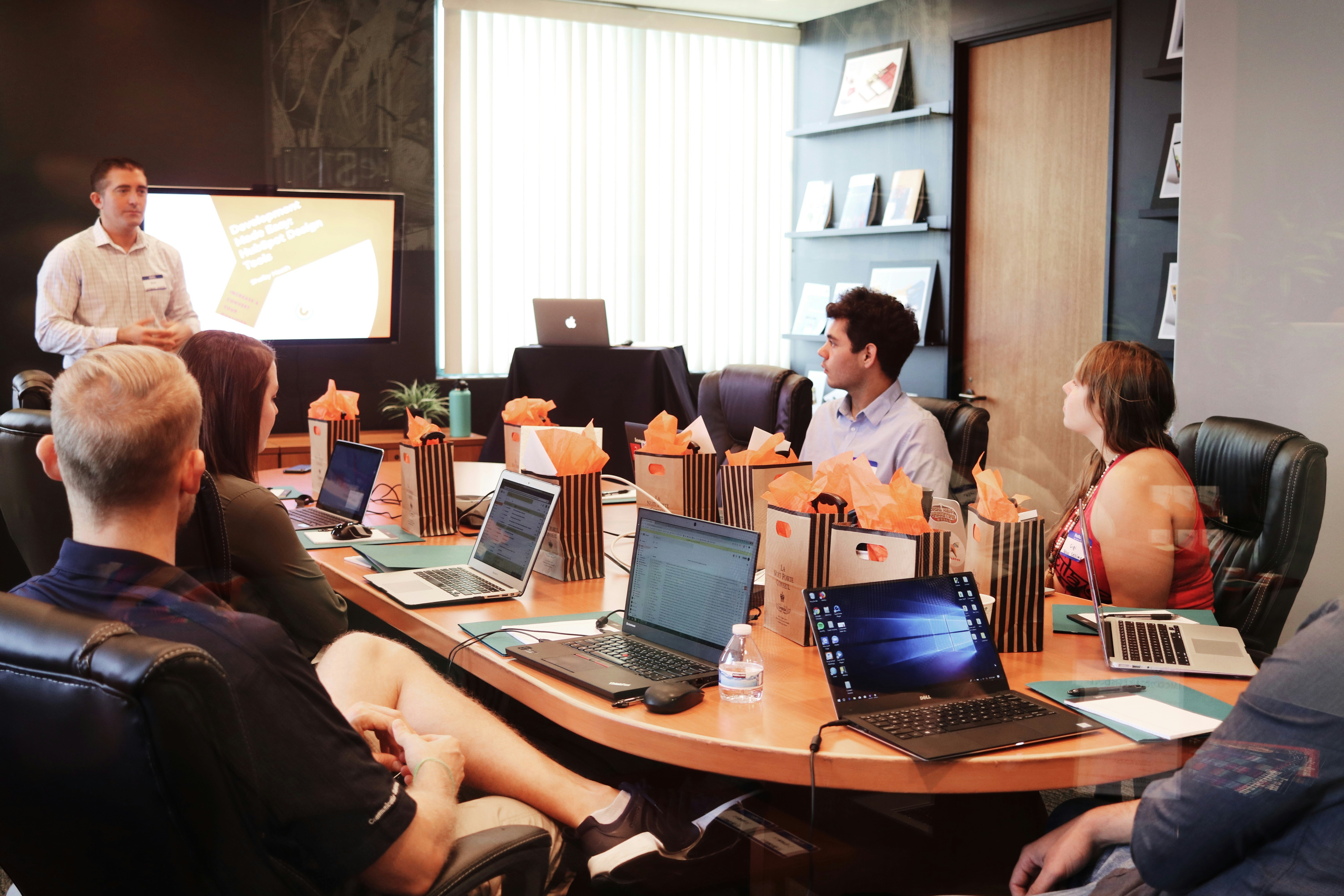 A diverse group of individuals sitting around a table, engrossed in their work on laptops.